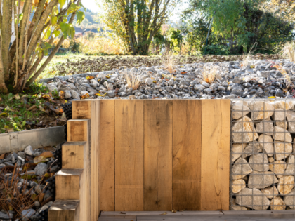 Mix des matières pour un mur de soutènement en bois et gabions avec un paillage minéral