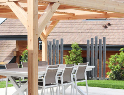 Pergola en bois posée sur une terrasse, créant un espace ombragé dans un jardin aménagé par ID Jardins.