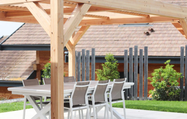 Pergola en bois posée sur une terrasse, créant un espace ombragé dans un jardin aménagé par ID Jardins.